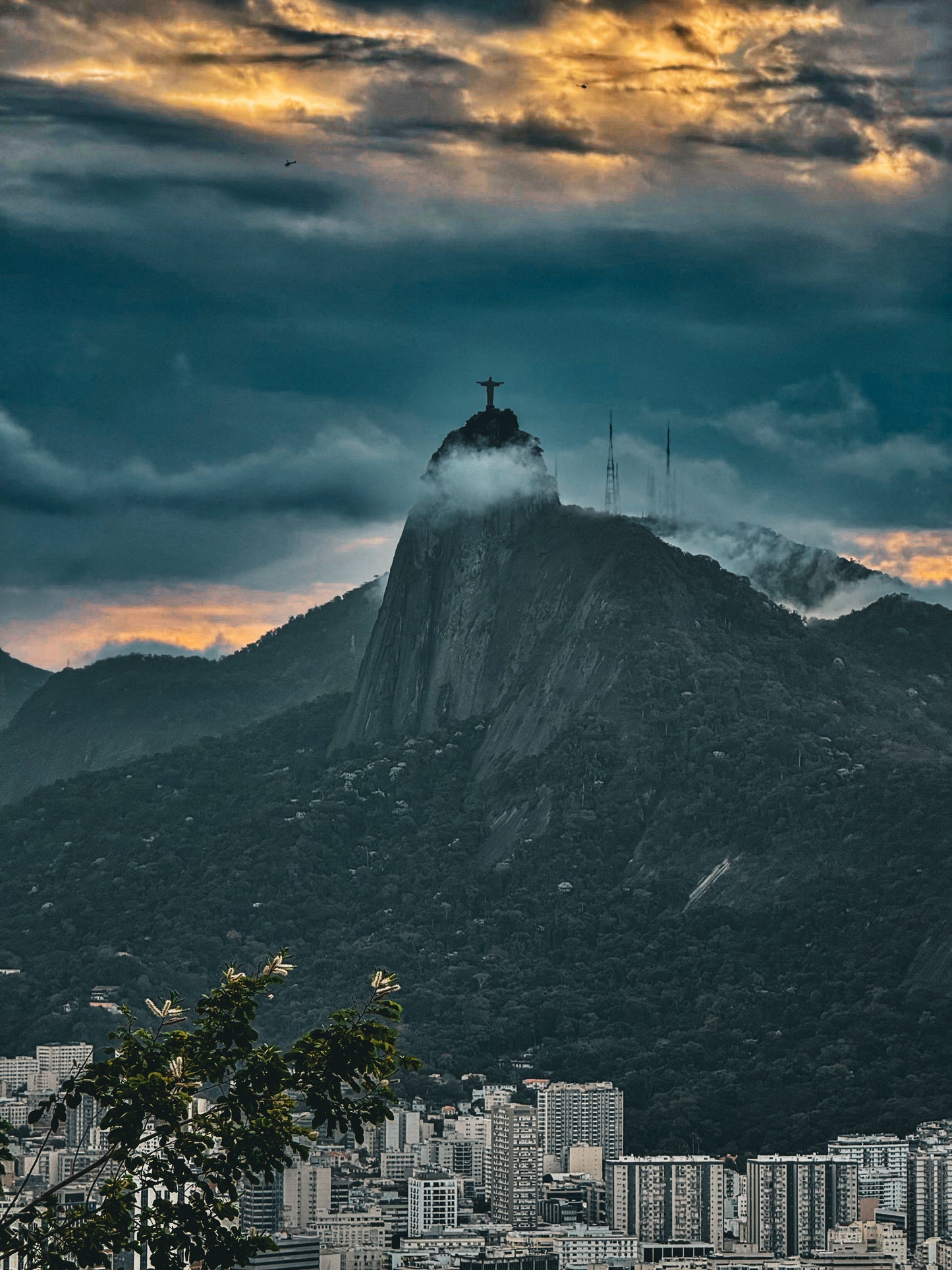 Christ the Redeemer Amidst a Dramatic Sky - Fine Art Print by Leslie Brashear Photography captures the iconic statue perched on Corcovado Mountain, soaring above Rio's cityscape under a breathtaking sunset sky.