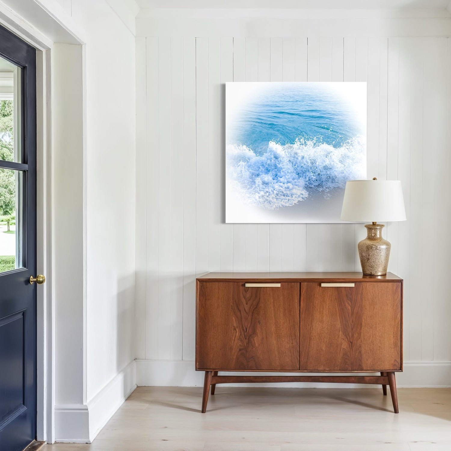 Wooden sideboard in a room with an artistic photo of ocean waves on the wall.